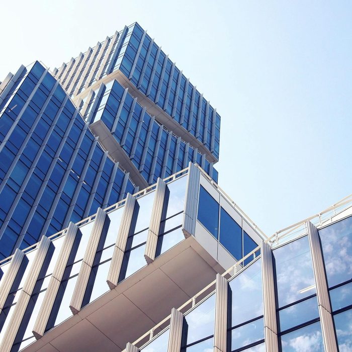 Low Angle Shot Of A Modern Skyscraper With Reflective Glass Design Under A Clear Blue Sky.