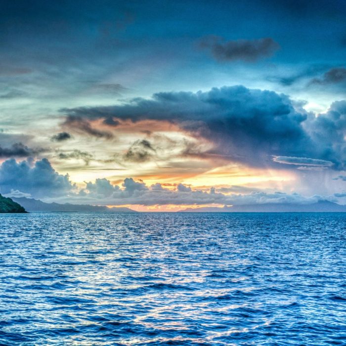 Vibrant Sunset Over Tropical Ocean With Dramatic Clouds And Distant Island.