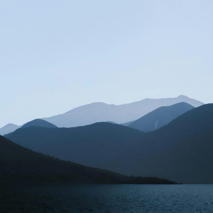 Serene Mountain And Lake View With Soft Silhouettes At Twilight.