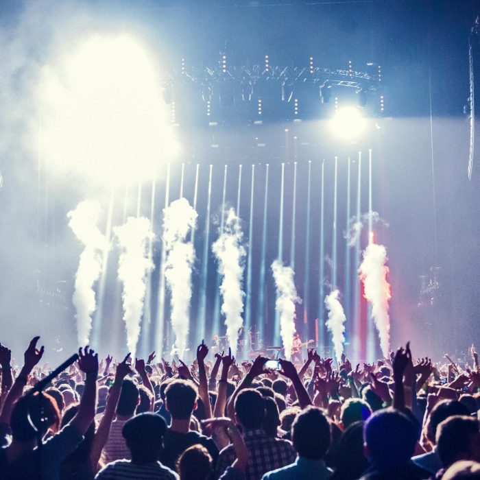 Vibrant Concert Scene With Cheering Crowd And Bright Stage Lights Creating An Electric Atmosphere.