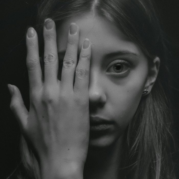 A Striking Black And White Portrait Of A Young Woman With A Contemplative Expression, Shot In A Studio.