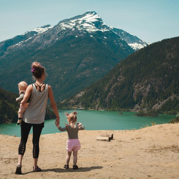 A Mother With Two Children Enjoys A Scenic Mountain And Lake View During A Sunny Outdoor Hike.