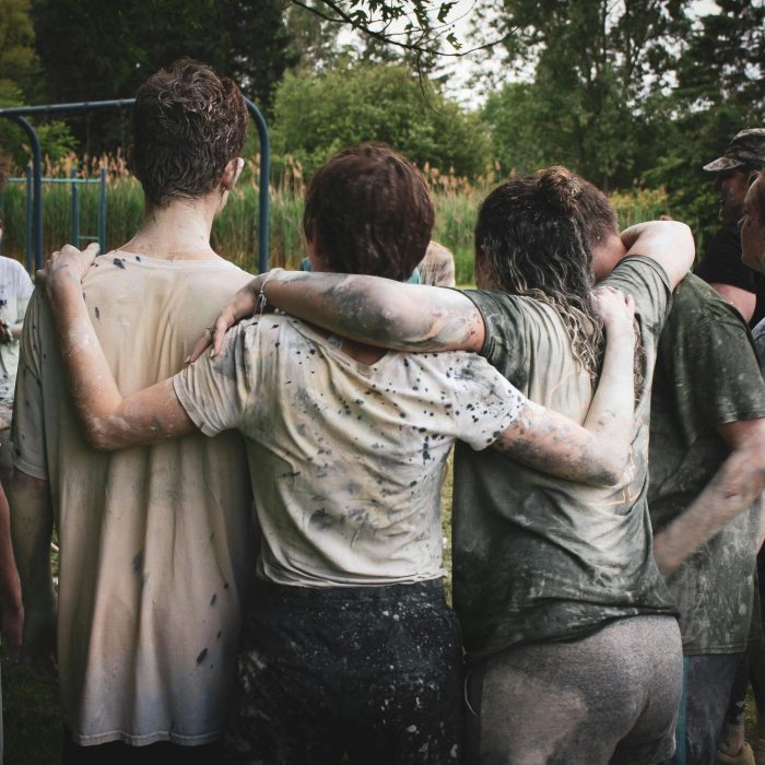 Group Of Teenagers Bonding In A Muddy Team Building Exercise Outdoors.