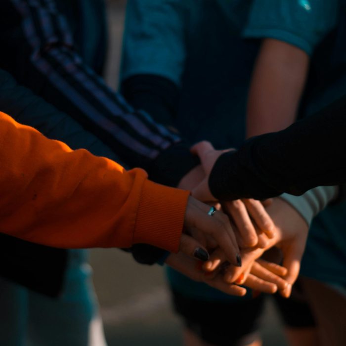 A Close Up Of Diverse Hands Stacked Together Outdoors, Symbolizing Teamwork And Unity.