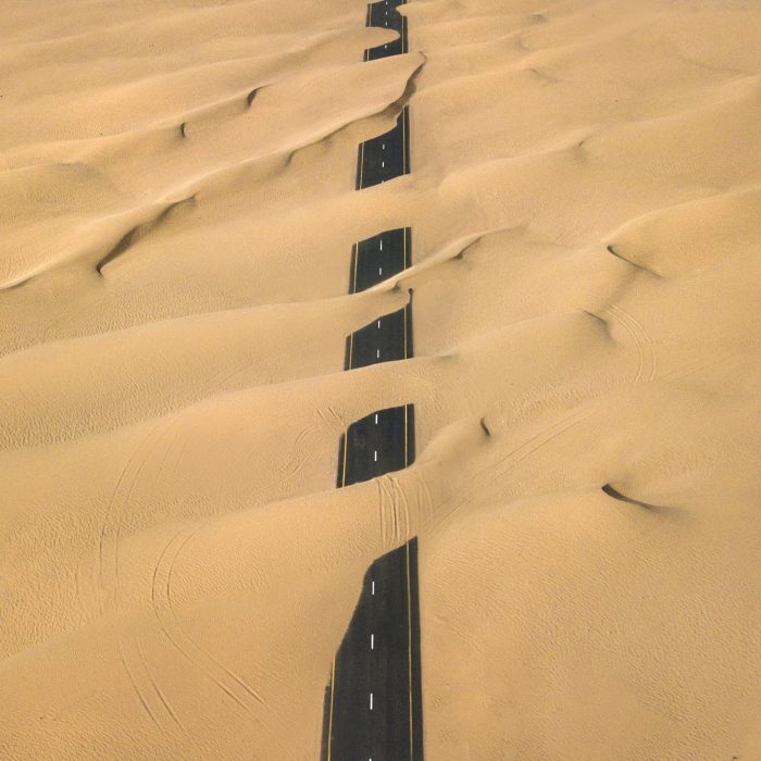 Stunning Aerial Shot Of A Road Cutting Through The Sand Dunes In Dubai's Desert.