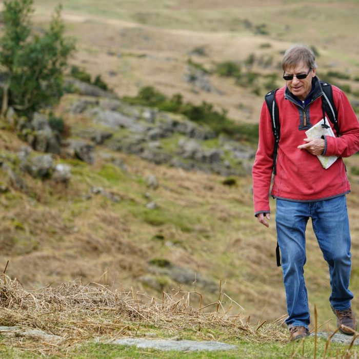 An Elderly Man Hiking With A Backpack And Map In The Scenic Cumbria Countryside, England.