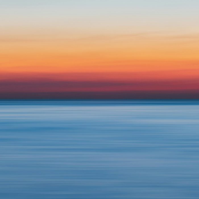 A Colorful Sunset Over A Calm Ocean, Perfect For Vibrant Backgrounds.