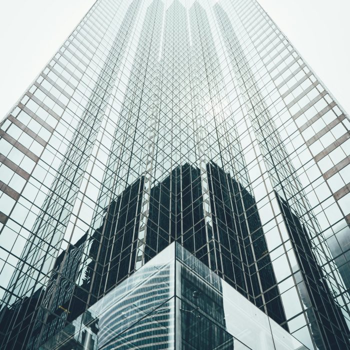 Striking Low Angle View Of A Modern Skyscraper With Reflective Glass Facade In A Cityscape.