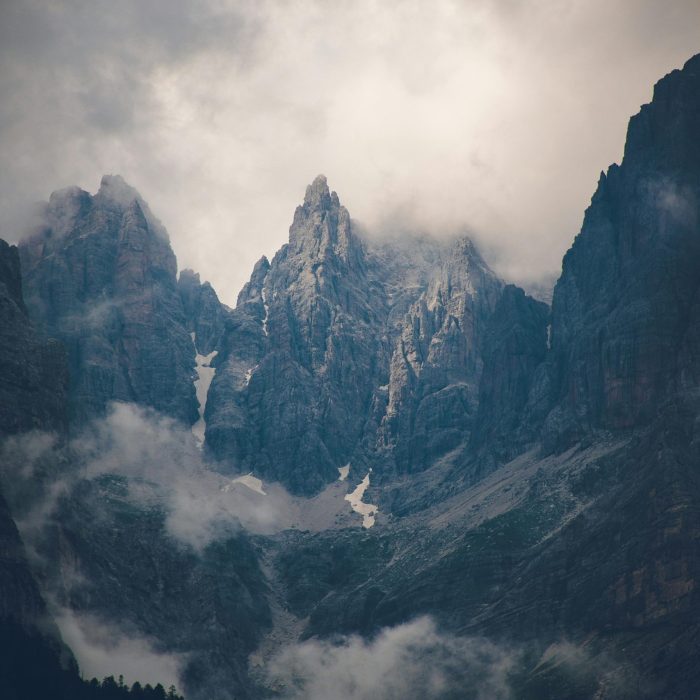Scenic View Of Dramatic Mountain Peaks Shrouded In Clouds.