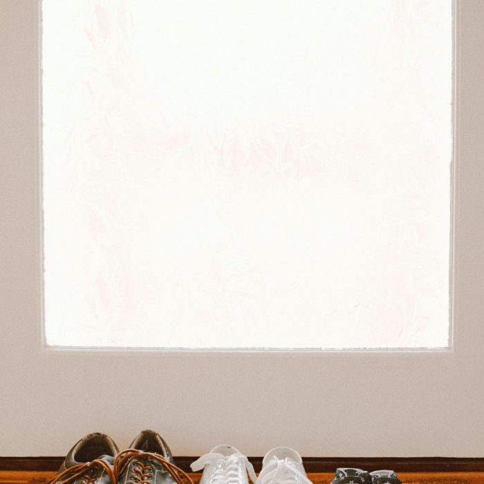 A Collection Of Family Shoes, Including Baby Booties, On A Welcoming Mat By The Door.