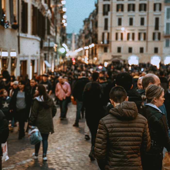 A Vibrant Street Filled With People In The Evening, Showcasing Urban Life And City Architecture.