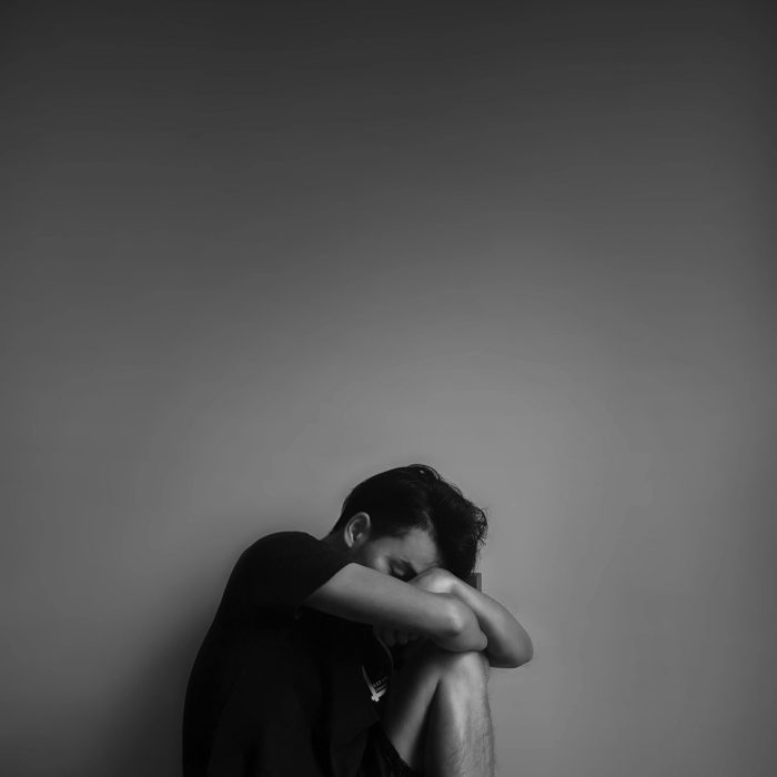 A Black And White Portrait Of A Man Sitting Alone, Evoking Emotion And Contemplation.