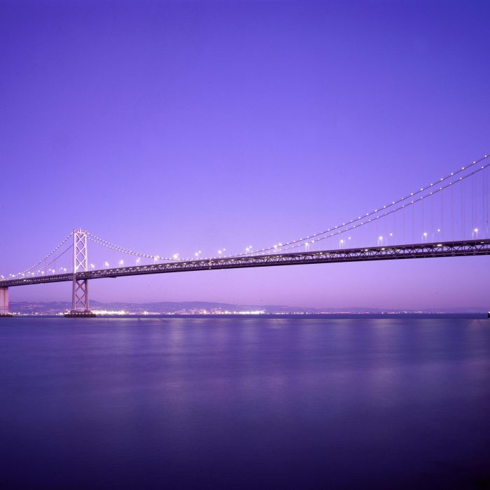 Beautiful View Of The Bay Bridge Lit Up At Twilight Against A Vibrant Purple Sky.