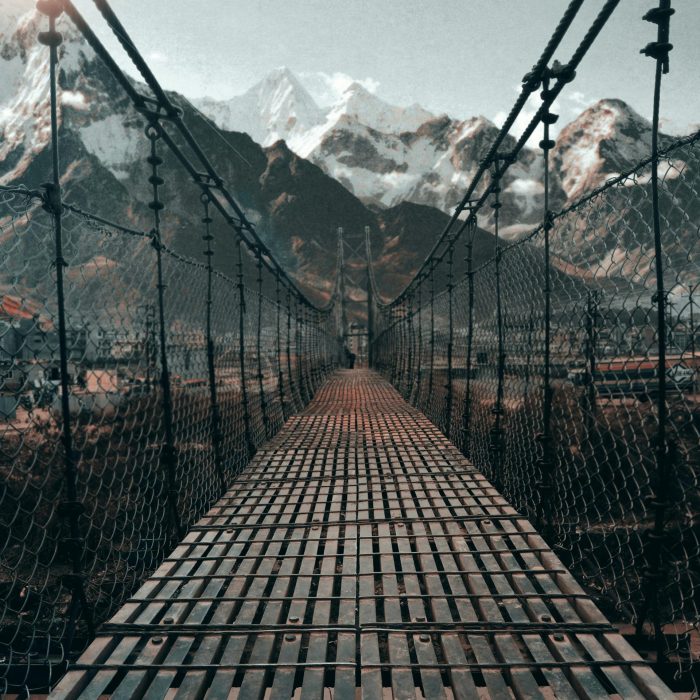 Breathtaking View Of A Suspension Bridge Leading To The Snowy Himalayan Mountains In Nepal.