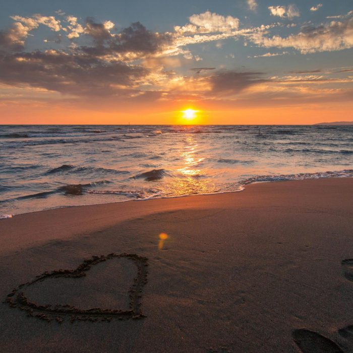 Beautiful Sunset Over Ocean With A Heart Shape In The Sand, Perfect For Romantic Themes.