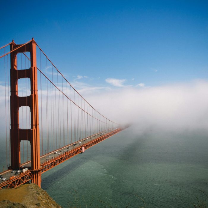 Stunning View Of Golden Gate Bridge Partially Covered By Fog With Clear Blue Sky.
