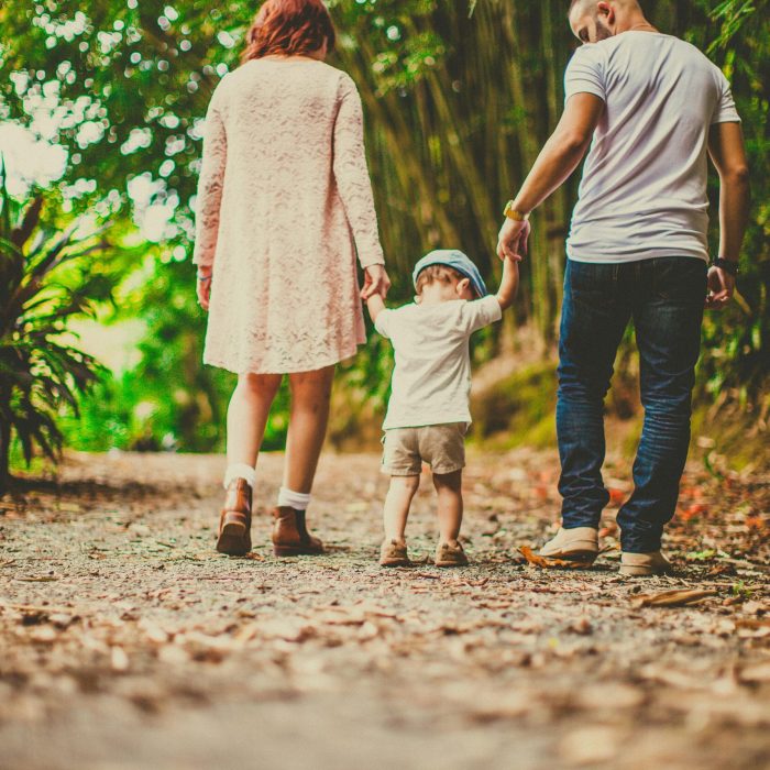 A Family Enjoys A Leisurely Walk In A Green Park, Embodying Joy And Togetherness.