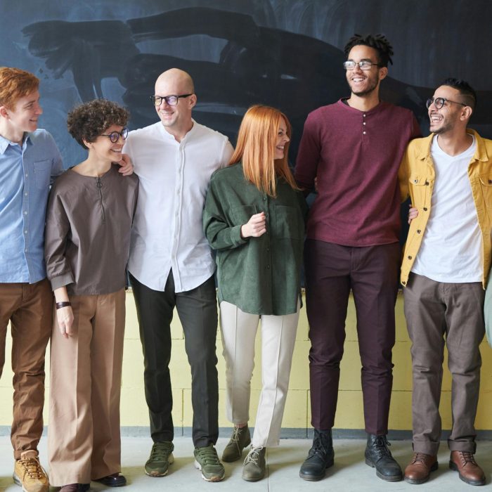 A Multicultural Group Of Six Adults Standing Happily Together In A Casual Setting.
