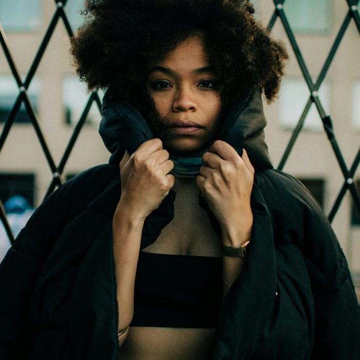 Portrait Of A Fashionable Woman Posing In A Black Puffer Jacket Outdoors.