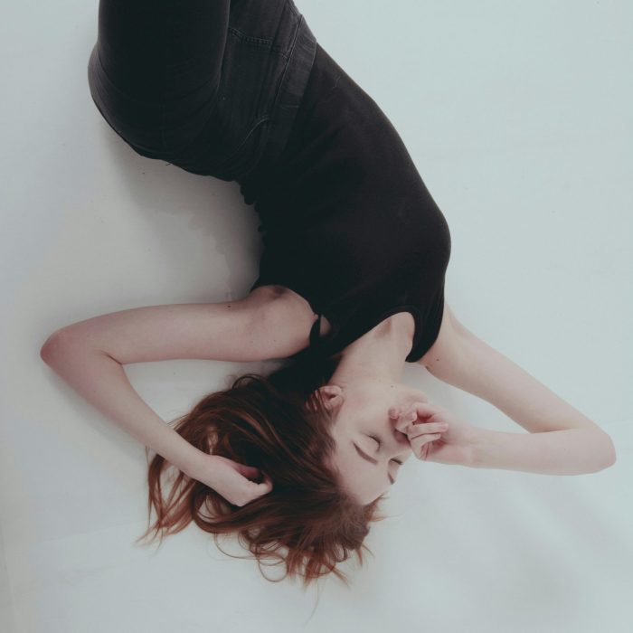 Stylish Portrait Of A Woman Lying Down In Black Attire With A Soft, Artistic Touch.