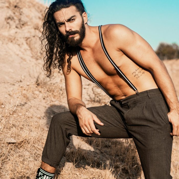 Portrait Of A Shirtless Man Wearing Suspenders Posing Outdoors In Summer.