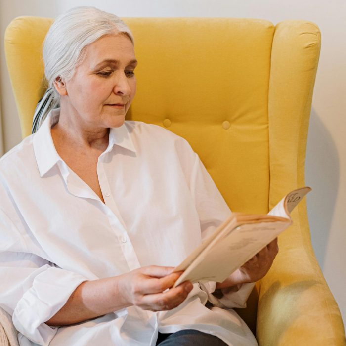 Senior Woman Enjoying A Quiet Reading Moment In A Cozy Home With A Warm Atmosphere.