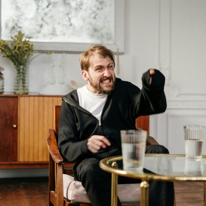 An Angry Man Expressing Emotion During A Therapy Session Indoors.