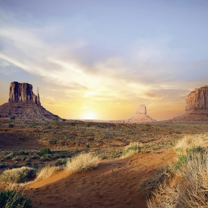 Breathtaking View Of Monument Valley's Iconic Rock Formations At Sunset, Showcasing Vivid Desert Landscape.