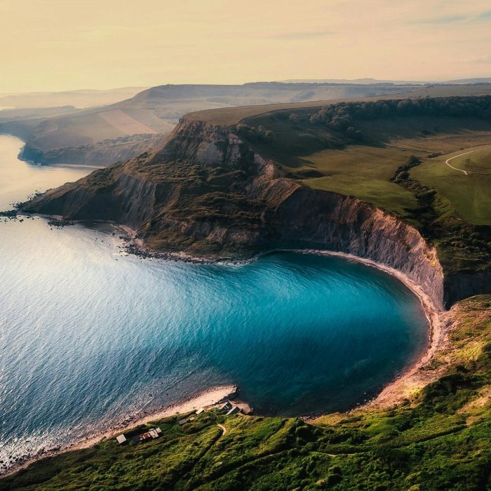 A Breathtaking Aerial View Of Coastal Cliffs With Turquoise Water And Lush Landscapes.