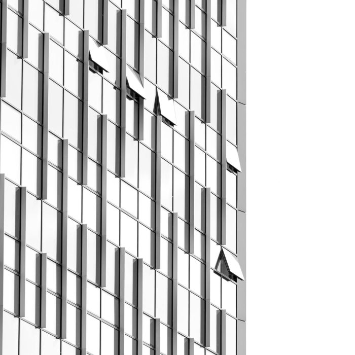 Low Angle View Of A Futuristic Skyscraper With Geometric Glass Facade And Reflections.