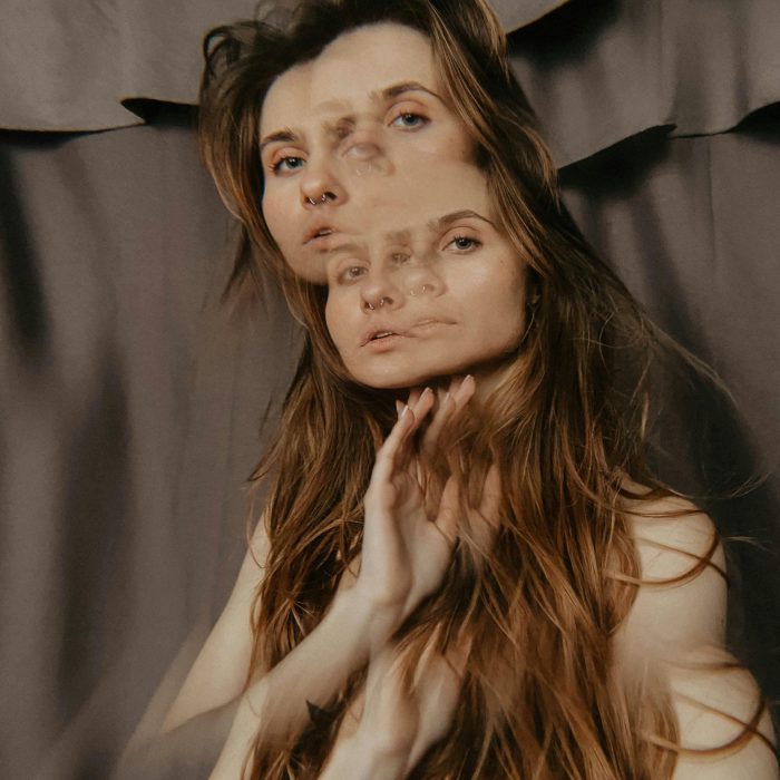A Creative Double Exposure Portrait Of A Woman With Long Brown Hair And A Blurred Abstract Appearance.