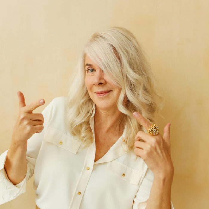 Elegant Senior Woman With White Hair Smiling And Posing Confidently Against A Neutral Background.