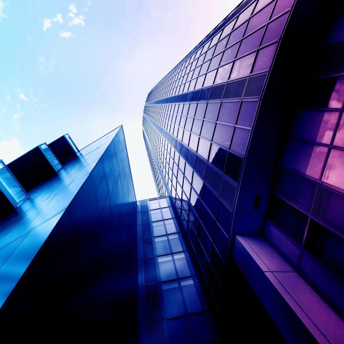 Low Angle Shot Of Modern Skyscrapers With Reflective Glass Facades And Vibrant Colors In An Urban Setting.