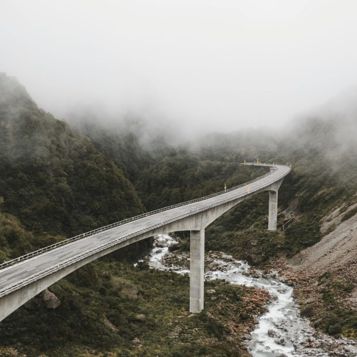 Scenic View Of A Bridge Over A River In A Foggy Mountain Landscape, Capturing Nature's Beauty.