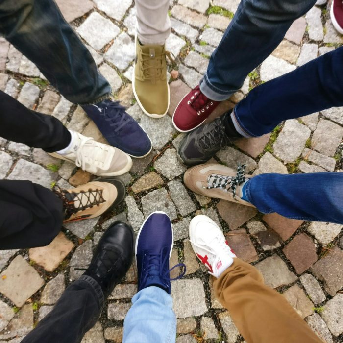 Circle Of Sneakers On Cobblestone Pavement Representing Diversity And Urban Fashion.