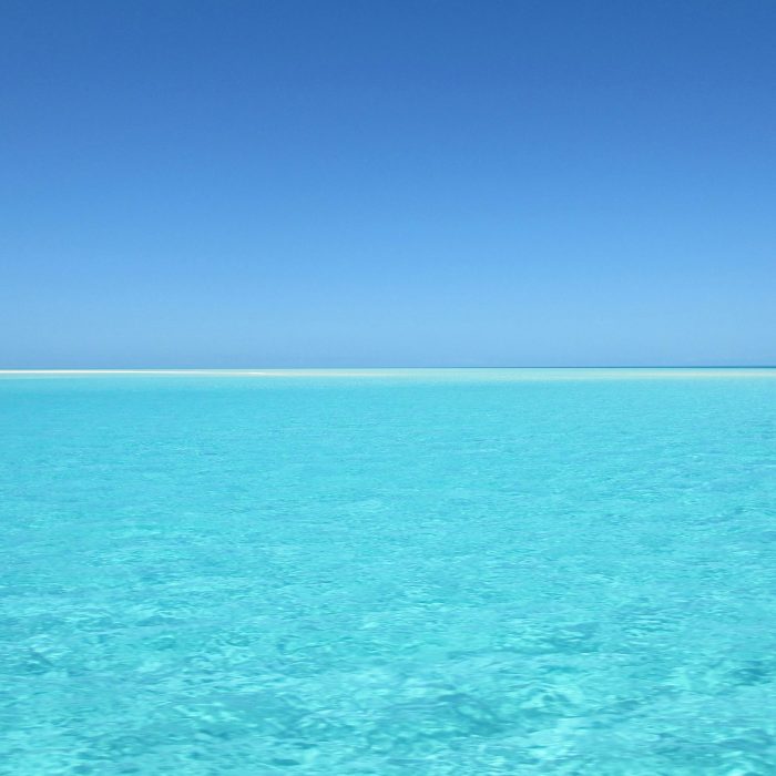 A Serene Blue Ocean With Crystal Clear Water Under A Vivid Blue Sky, Perfect For Relaxation.