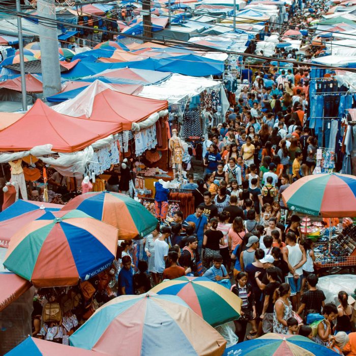 A Bustling Street Market In Manila With Colorful Tents And A Lively Crowd Shopping Outdoors.