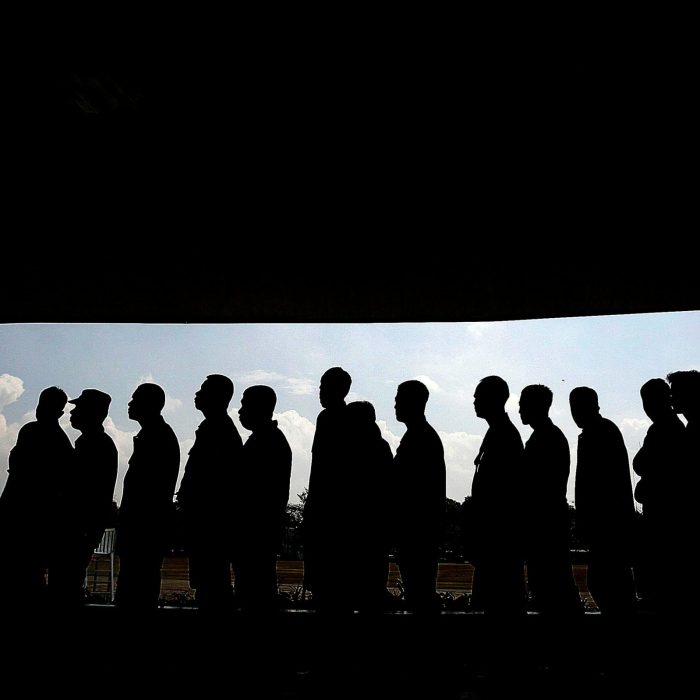 Silhouettes Of People In Line Under A Shaded Canopy, Highlighting Social Interaction And Society.