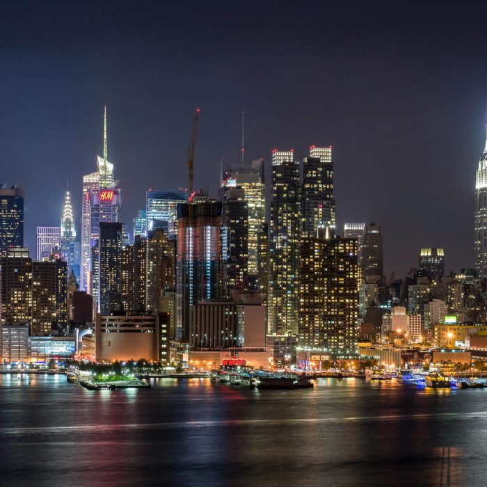 Stunning View Of The Illuminated New York City Skyline Reflecting On The Hudson River At Night.