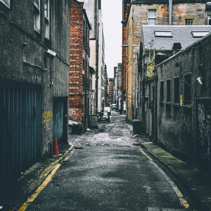 Quiet Urban Alley With Parked Cars Between Old Brick Buildings, Showcasing City Life.